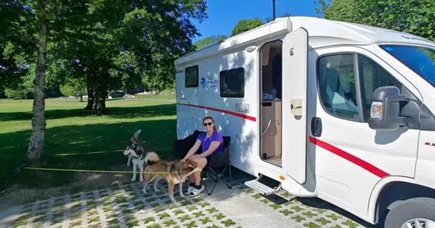 Two huskies with owner outside campervan at an Irish campsite
